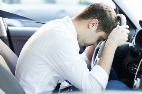 man slumping over steering wheel